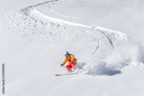 freeride skier skiing downhill through deep powder snow