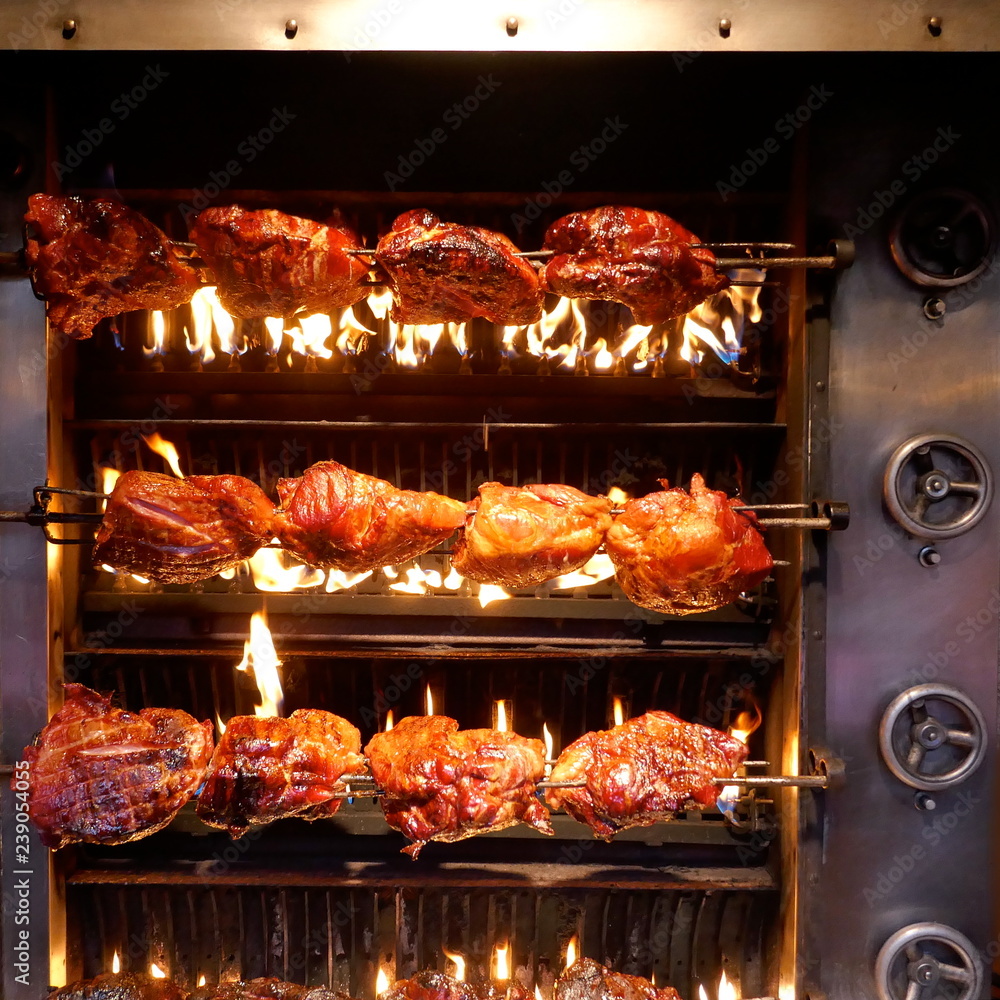 Roast pork on skewer over open charcoal fire in a rotisserie
