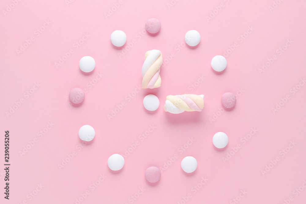 concept image, a clock with candy and marshmallow, pastel colors on pink