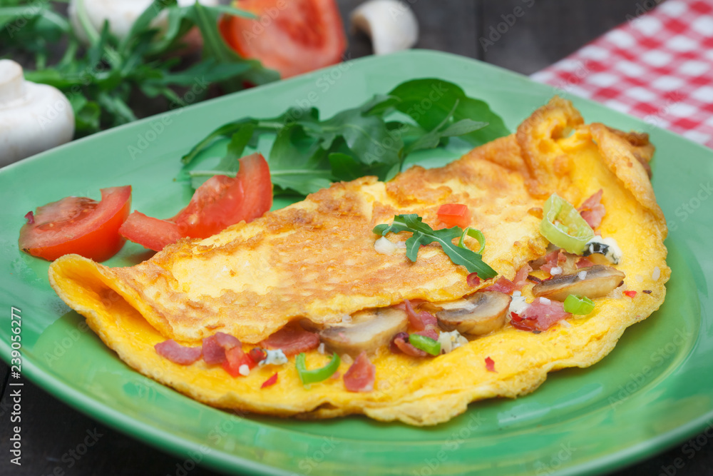 Homemade egg omlette for breakfast. Omlet garnished with tomato and rucola salad. Homemade egg omlette for breakfast. Omlet garnished with tomato and rucola salad.
