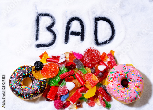 Close up of colorful sweets candies donuts with bad written in white sugar in unhealthy child diet