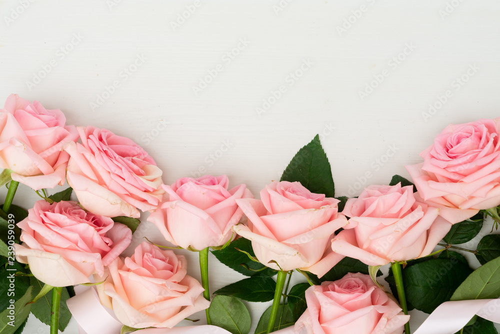 Rose fresh pink flowers border on light table from above with copy space, flat lay scene