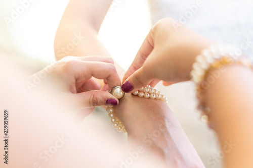 hands helping to put a bracelet on a bride