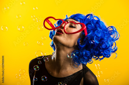 Cute girl wearing vibrant blue wig playing and blowing bubbles photo