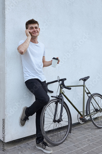 Handsome hipster man posing with bicycle in the city.