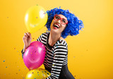 Cute Asian Woman playing with balloons and confetti wearing bright colorful wig and heart shaped glasses