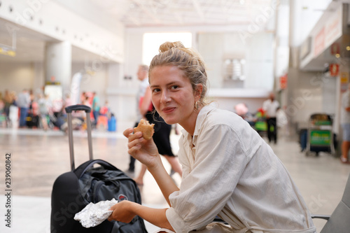 Young woman, authentic, natural, unplugged, waiting for her flight at the airport of Tenerife while eating a bun.