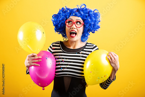 Cute Asian Woman playing with balloons and confetti wearing bright colorful wig and heart shaped glasses © Mat Hayward