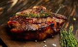steak on a wooden board, lemon, red pepper, garlic and seasonings on a dark rustic background