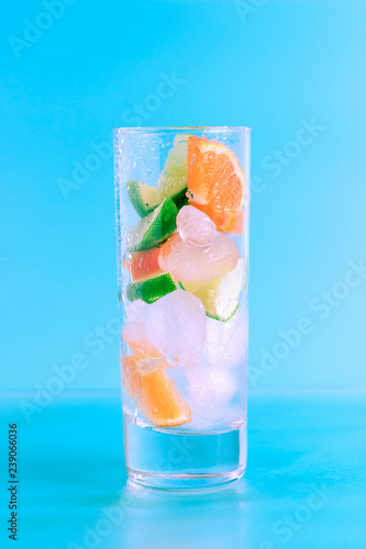 Fresh cocktail with lime, orange and ice on blue background. Summer background. photo