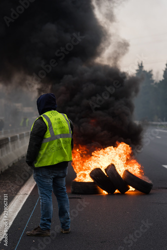 Gilet jaune de dos face à des pneus qui brûlent sur l'autoroute - Manifestation France décembre 2018