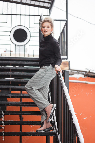 Stylish young woman with skateboard sitting on stairs
