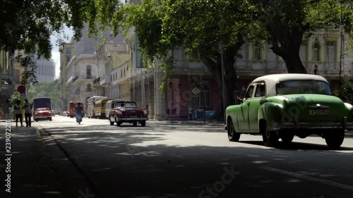  iconic old 1950's vintage classic american cars driving on famous alley street in old neighborhood Havana, Cuba