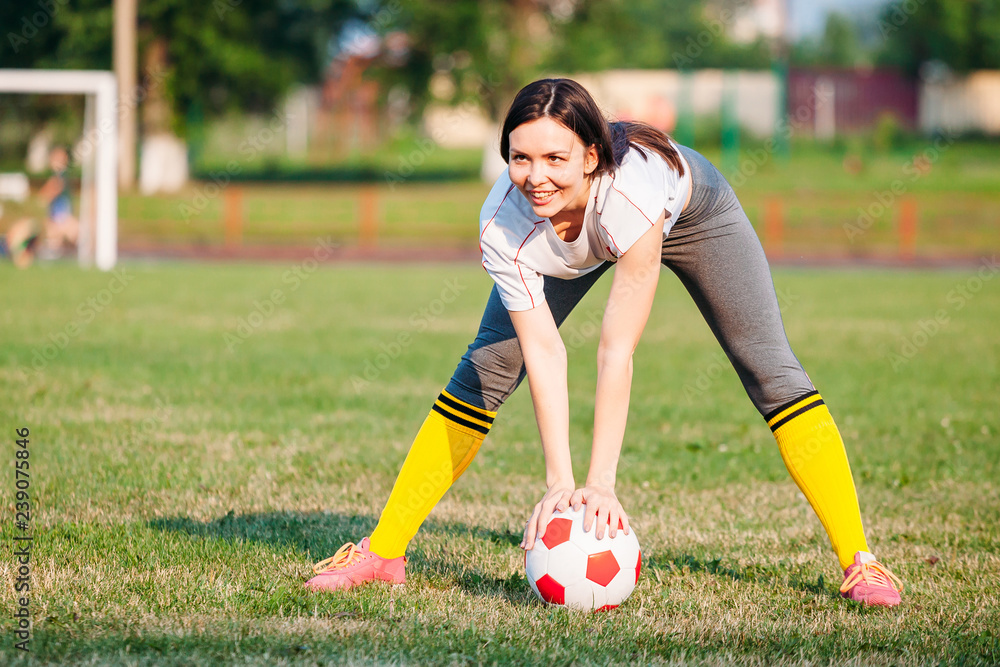 happy smile girl with soccer ball on football pitch. holding in hands ball
