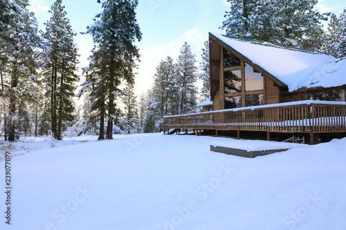 Chalet style Cider A-frame house in the mountains covered in snow with a large porch