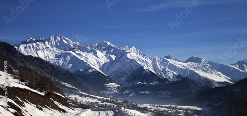 Panoramic view on snowy road and mountain in haze at early winter morning