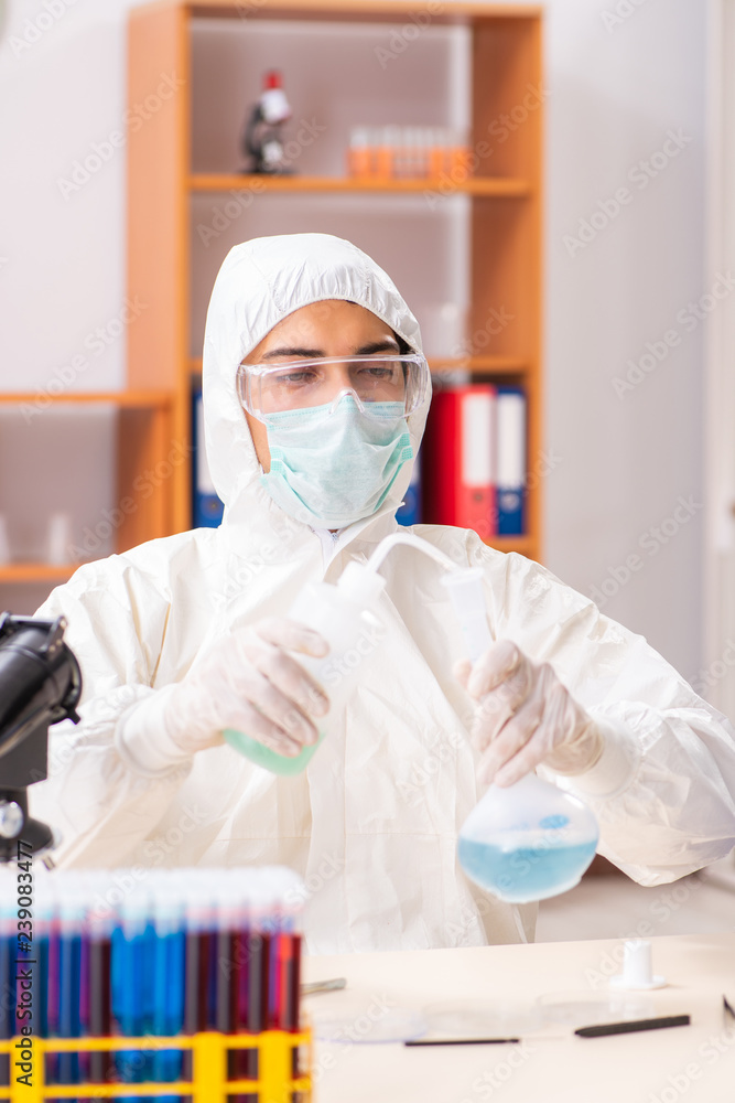 Young biochemist wearing protective suit working in the lab Young biochemist wearing protective suit working in the lab