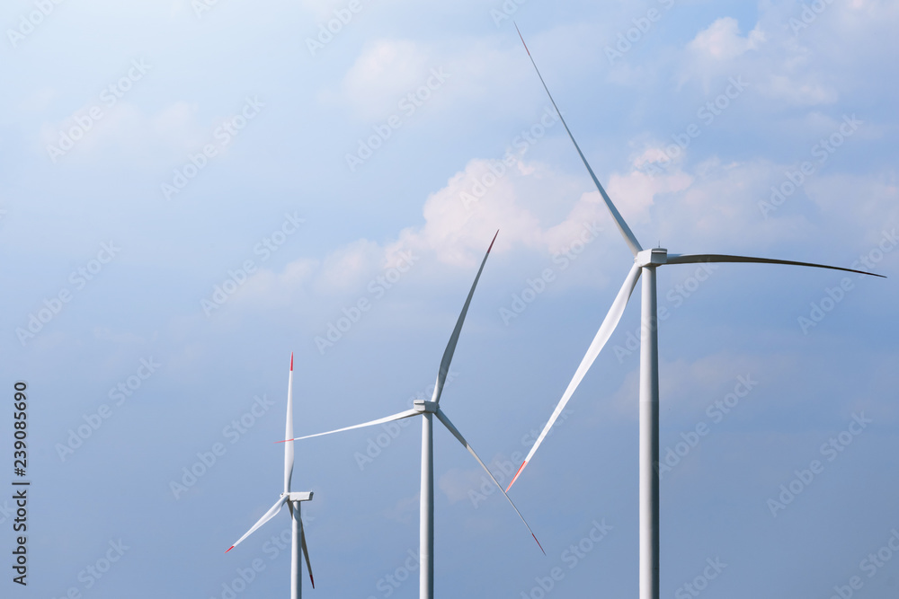 Windmill turbine farm with partly cloudy blue sky in background. Renewable energy wind turbines Windmill turbine farm with partly cloudy blue sky in background. Renewable energy wind turbines