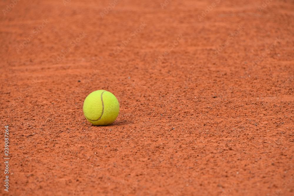 Yellow tennis ball on red clay ground court