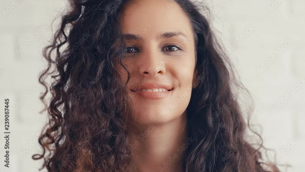 Portrait of beautiful young woman with curly hair on a white wall, 4k 75 fps slow motion Portrait of beautiful young woman with curly hair on a white wall, 4k 75 fps slow motion