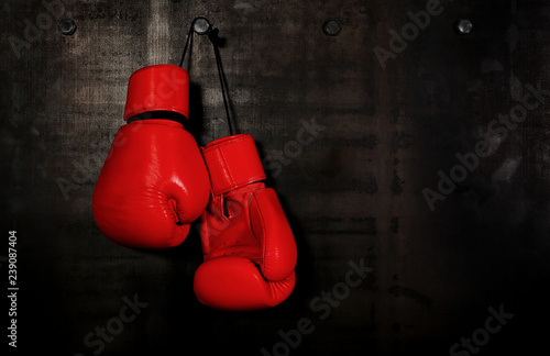 Red leather boxing gloves hanging on black wall
