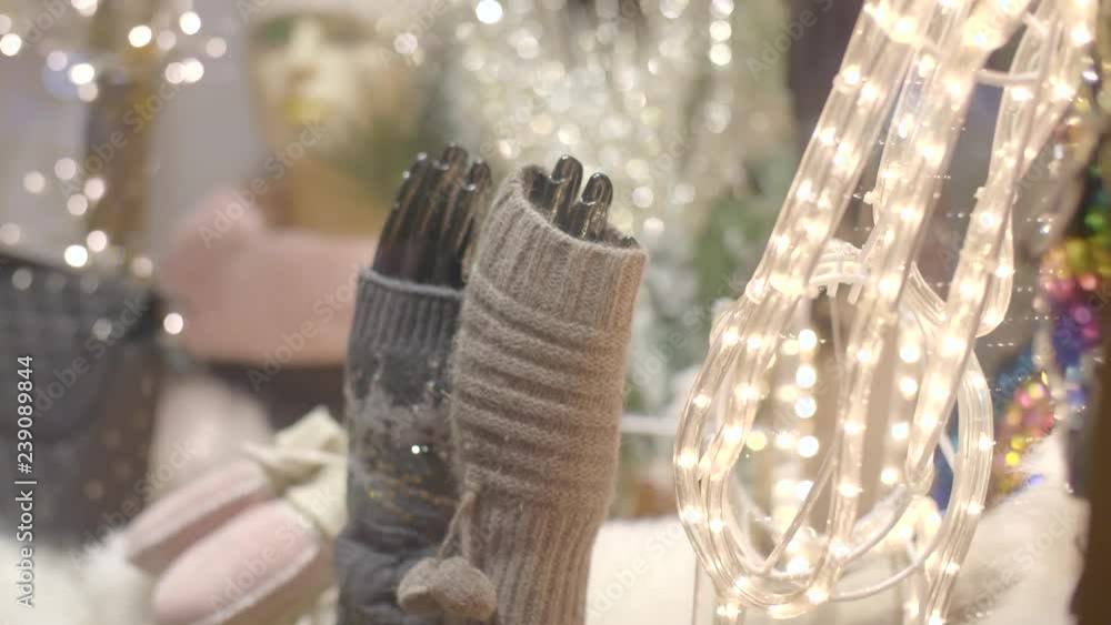 Natural wool knitted gloves,mittens without fingers or gaiters in illuminated shop window at night. Comfortable,warm clothes for cold winter. Consumerism,gift or present, christmas holidays concept Natural wool knitted gloves,mittens without fingers or gaiters in illuminated shop window at night. Comfortable,warm clothes for cold winter. Consumerism,gift or present, christmas holidays concept