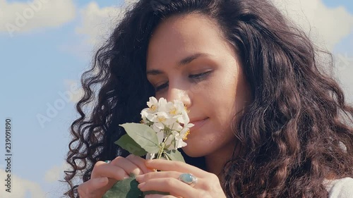 Beautiful caucasian young woman with curly hair smelling flower, 4k 75 fps slow motion