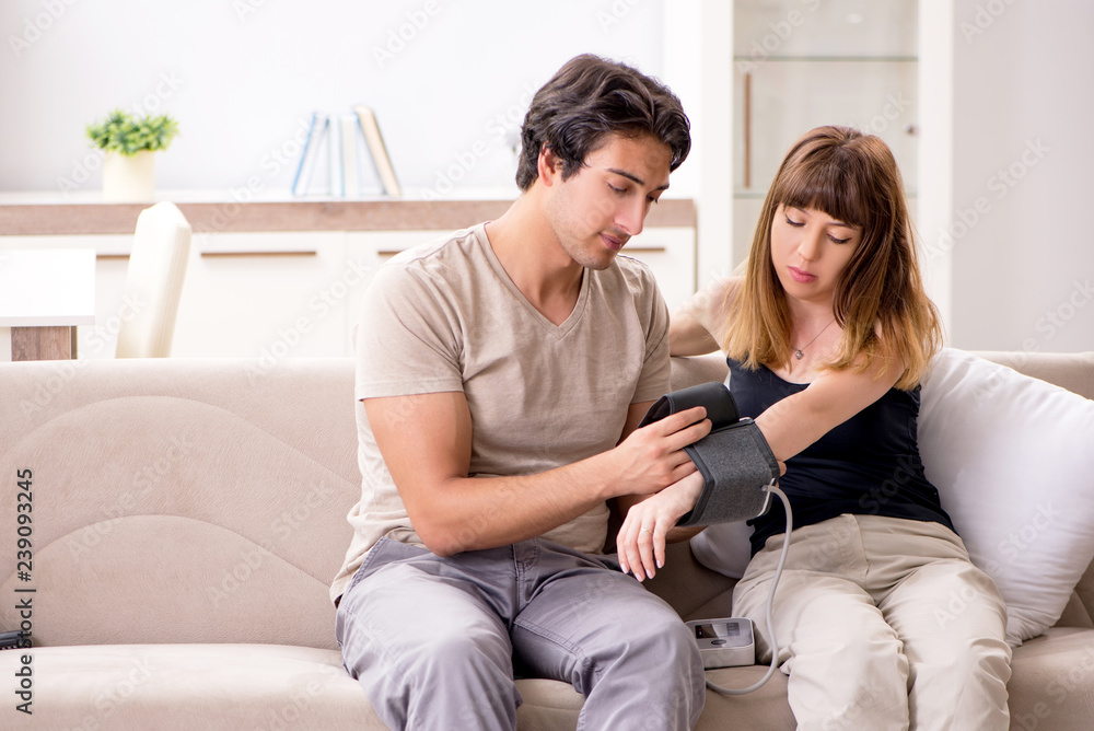 Husband checking wife's blood pressure
