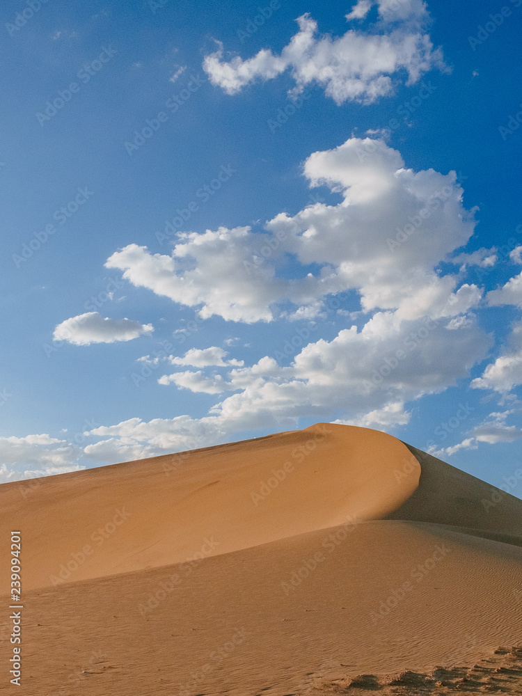 Sand dunes and desert under blue sky at Mingsha Mountain, in Dunhuang, Gansu, China