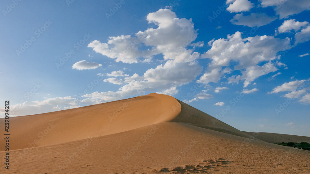 Sand dunes and desert under blue sky at Mingsha Mountain, in Dunhuang, Gansu, China