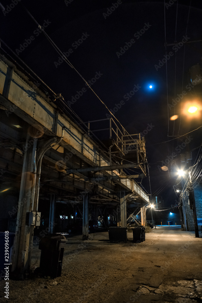 Dark and eerie urban city alley with a vintage railway bridge and the moon at night Dark and eerie urban city alley with a vintage railway bridge and the moon at night