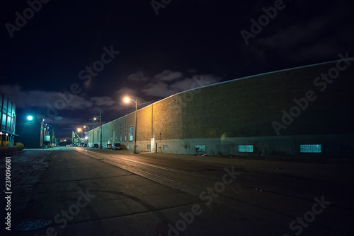 Industrial urban street city night scene with vintage factory warehouses and train tracks photo