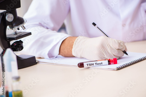 Young handsome lab assistant testing blood samples in hospital  photo