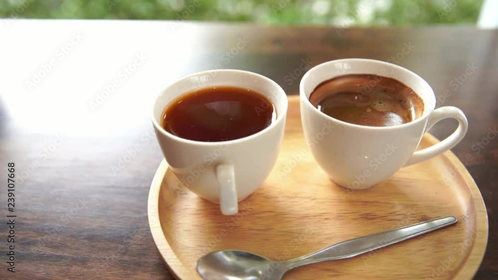 Coffee in white cup on wooden table, handheld shot