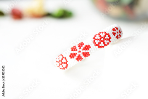 White beaded bracelet with red flower print close up