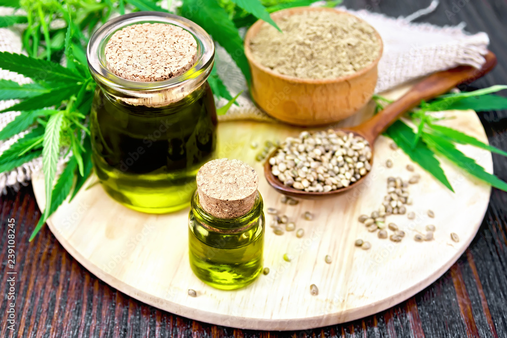 Oil hemp in two jars with flour on dark board Oil hemp in two jars with flour on dark board