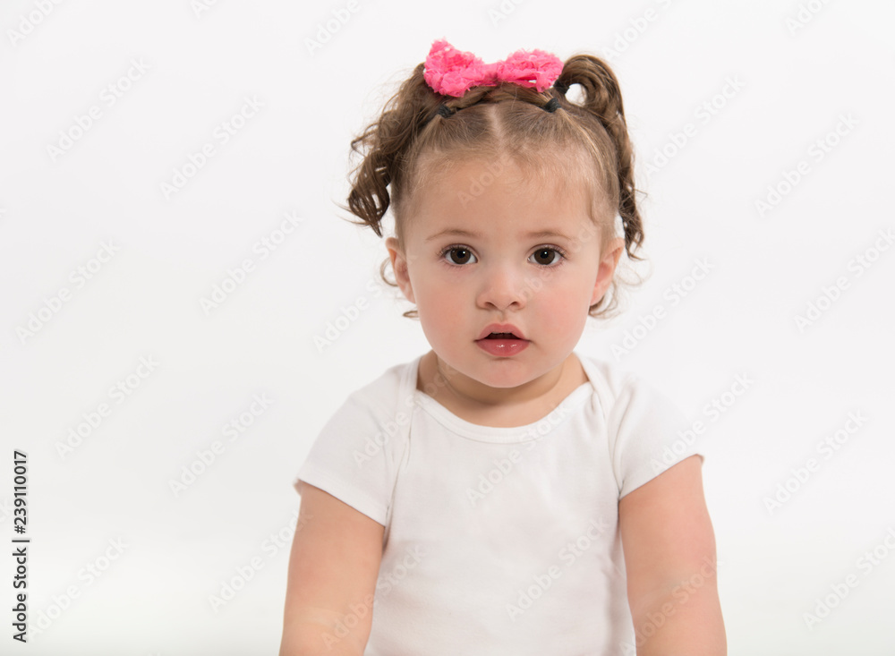 Sweet, serious, brown eyed baby girl, with pink hair bow sitting on white  background Stock Photo | Adobe Stock