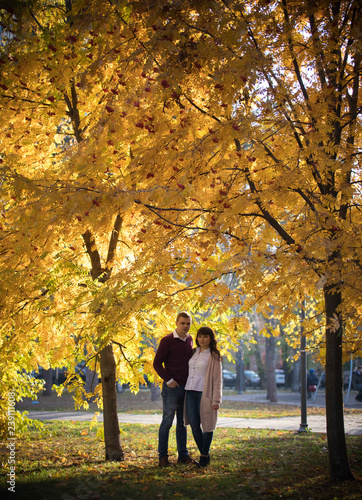 A couple in love stands among the autumn trees in the park
