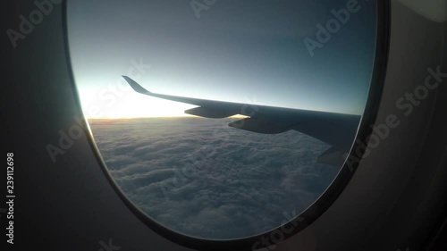 Airplane flying above clouds at sunset, view of wing from plane window. photo