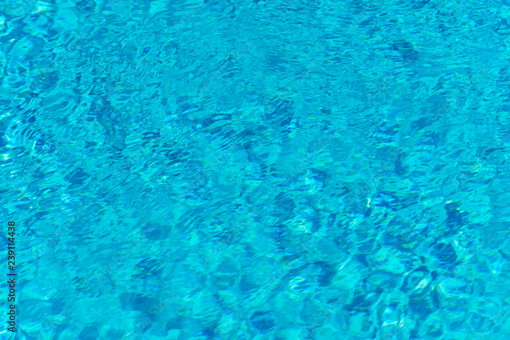 Blue water in swimming pool background. Ripple Water in swimming pool with sun reflection. Blue swimming pool rippled water detail.