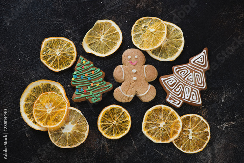 Crispy fruit chips made of orange and gingerbread cookies over dark brown stone background, flatlay