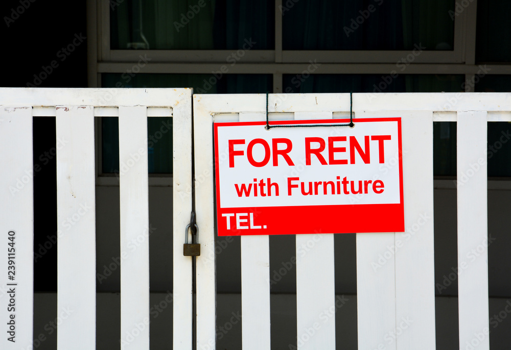 red sign on white background with the inscription house for rent with furniture hanging on closed white fence, copy space red sign on white background with the inscription house for rent with furniture hanging on closed white fence, copy space