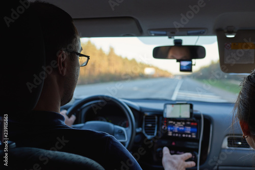 European man with the girlfriend by his side is driving the car on the roadway. © Artem