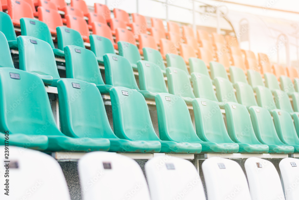 Fototapeta premium Plastikowe siedziska w kolorze białym, czerwonym i miętowym, ustawione w rzędach na stadionie. Pojęcie zdrowego stylu życia, nieostrość.