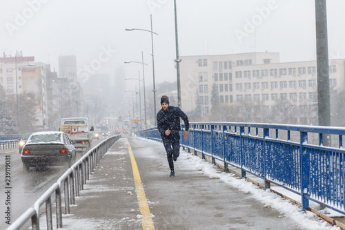 Young man running in city street at cold winter day. © Zoran Zeremski