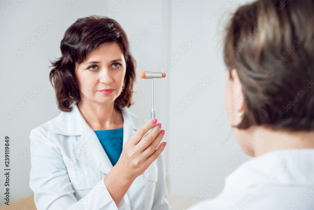 Neurological examination. The neurologist testing reflexes on a female patient using a hammer. Neurological examination. The neurologist testing reflexes on a female patient using a hammer.