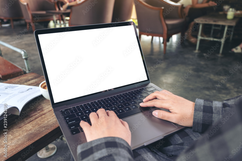 Mockup image of hands using and typing on laptop with blank white desktop screen while sitting in cafe Mockup image of hands using and typing on laptop with blank white desktop screen while sitting in cafe