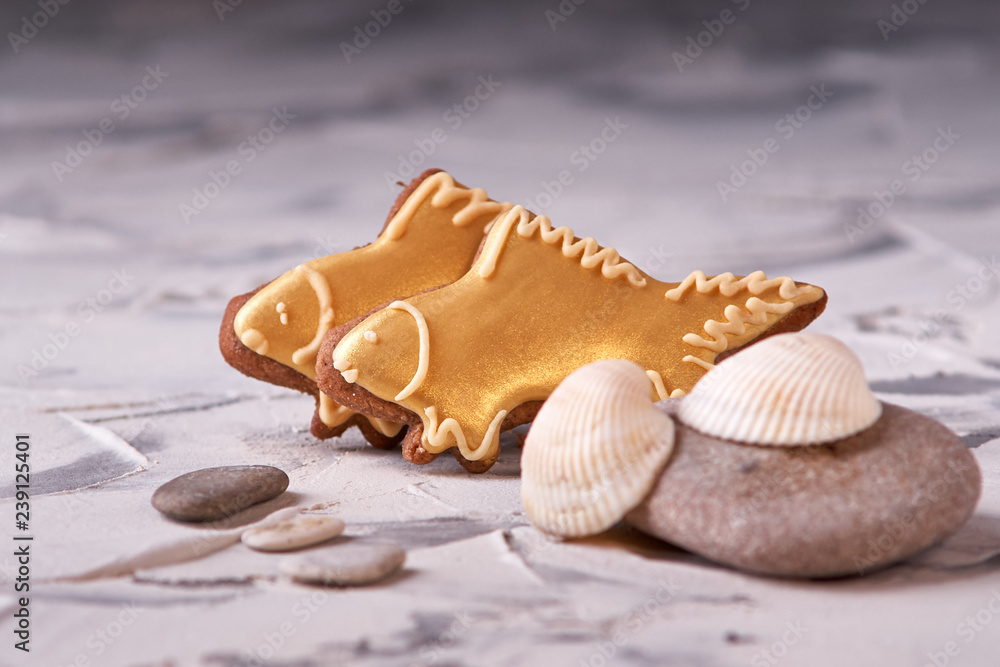 Sweet goldfish cookies and shells on gray background