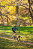 The girl rides a bike in the autumn park.