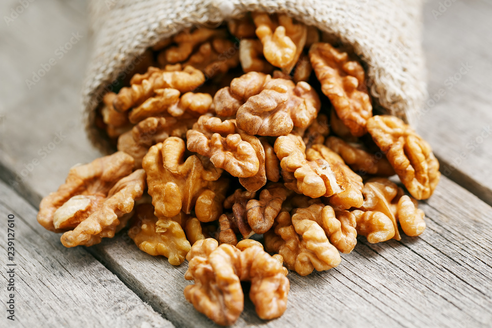 Walnuts in a burlap bag on a wooden gray background. Walnuts in a burlap bag on a wooden gray background.